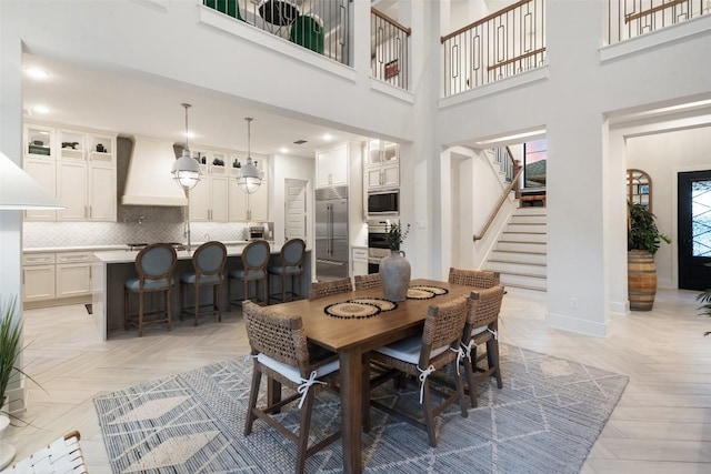 dining space featuring recessed lighting, baseboards, stairs, and a towering ceiling