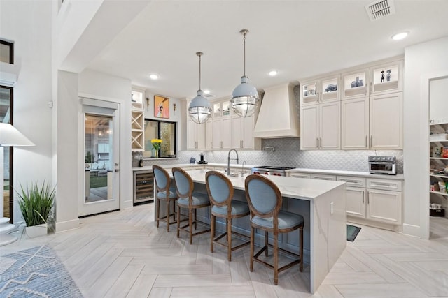 kitchen with backsplash, visible vents, custom exhaust hood, and wine cooler