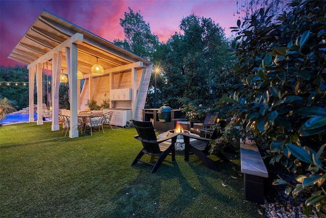 yard at dusk with an outdoor fire pit, a patio area, and an outdoor pool