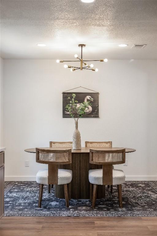 12305 Rustic Manor Ct, Austin, TX 78750 - dining space featuring wood finished floors, a chandelier, and a textured ceiling
