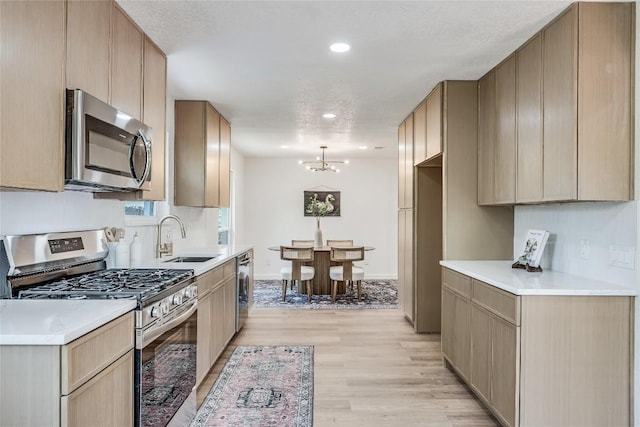 12305 Rustic Manor Ct, Austin, TX 78750 - kitchen featuring appliances with stainless steel finishes, light wood-type flooring, a chandelier, light countertops, and recessed lighting
