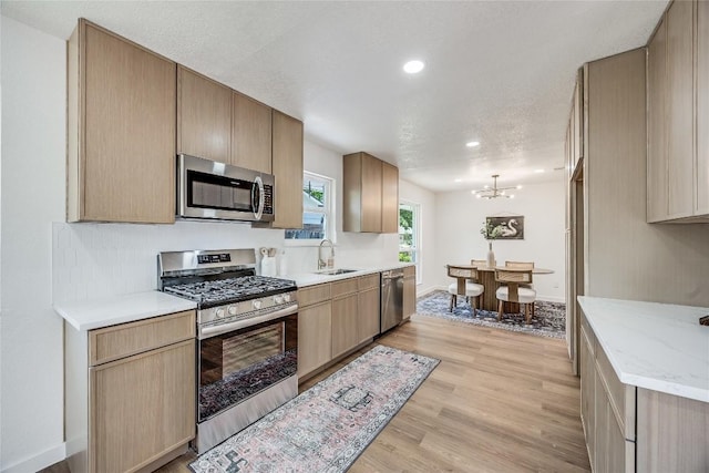 12305 Rustic Manor Ct, Austin, TX 78750 - kitchen with appliances with stainless steel finishes, light wood finished floors, recessed lighting, a chandelier, and light stone countertops
