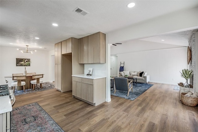 12305 Rustic Manor Ct, Austin, TX 78750 - kitchen with light wood finished floors, a textured ceiling, light countertops, a chandelier, and open floor plan