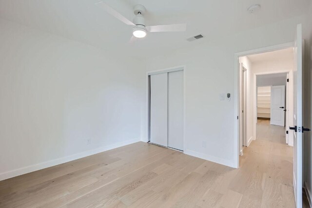 unfurnished bedroom featuring light wood finished floors, visible vents, a closet, and baseboards