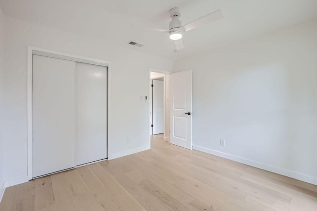 unfurnished bedroom featuring baseboards, a closet, light wood-style flooring, a ceiling fan, and visible vents