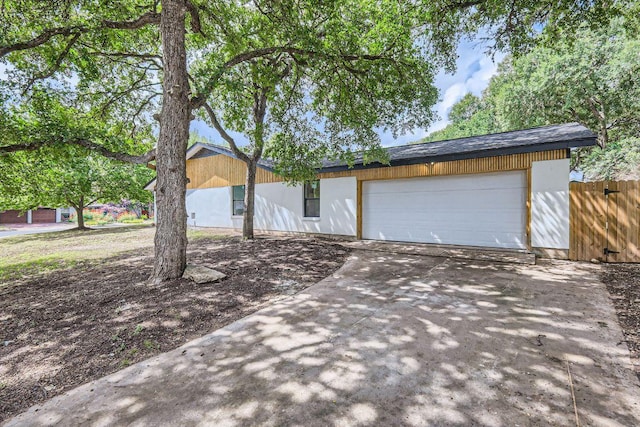 view of front of home with concrete driveway, fence, and a garage