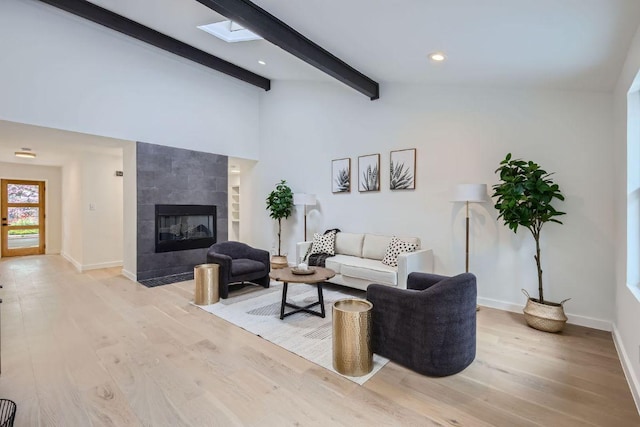 living room with light wood-style flooring, lofted ceiling with skylight, baseboards, and a fireplace