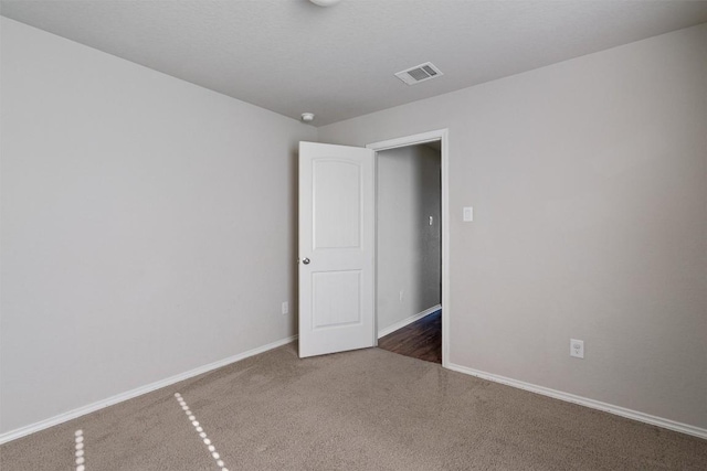 carpeted spare room featuring visible vents and baseboards