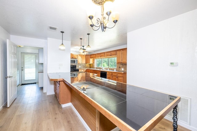 1229 State Highway 304, Gonzales, TX 78629 - kitchen featuring stainless steel microwave, light wood-type flooring, tasteful backsplash, and brown cabinets