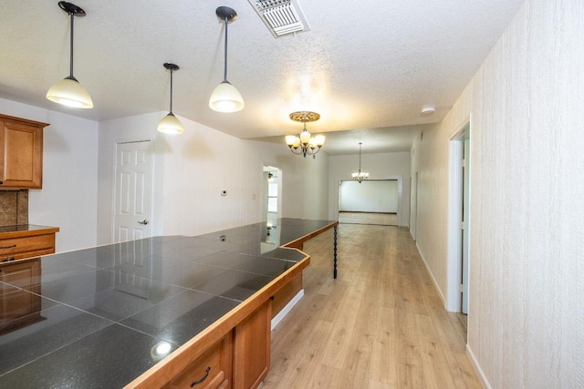 1229 State Highway 304, Gonzales, TX 78629 - kitchen with brown cabinetry, a chandelier, light wood finished floors, decorative light fixtures, and a textured ceiling