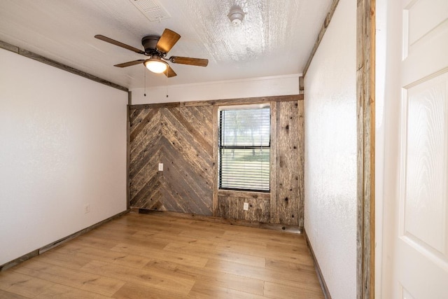 1229 State Highway 304, Gonzales, TX 78629 - empty room with light wood-type flooring, ceiling fan, wooden walls, and crown molding