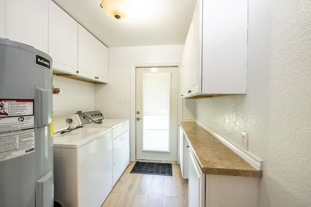 1229 State Highway 304, Gonzales, TX 78629 - washroom featuring separate washer and dryer, a textured wall, cabinet space, electric water heater, and light wood finished floors