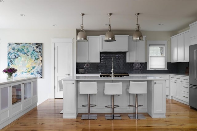 606 E 42nd St, Austin, TX 78751 - kitchen featuring a kitchen island with sink, decorative backsplash, light countertops, a kitchen bar, and recessed lighting