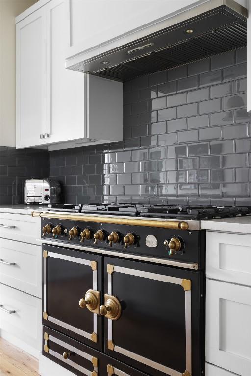 606 E 42nd St, Austin, TX 78751 - kitchen with double oven range, ventilation hood, white cabinets, and backsplash