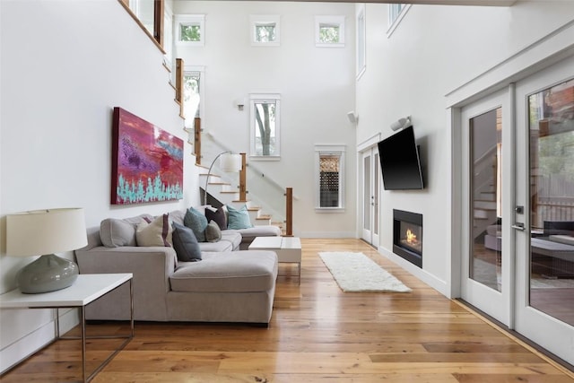 606 E 42nd St, Austin, TX 78751 - living area featuring stairs, light wood-style flooring, a high ceiling, a glass covered fireplace, and baseboards
