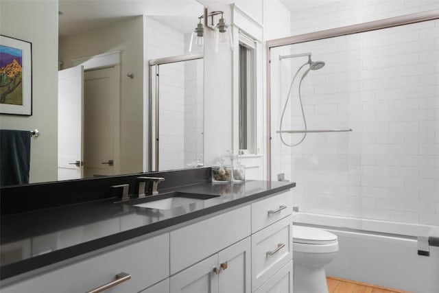 606 E 42nd St, Austin, TX 78751 - bathroom with vanity, toilet, bath / shower combo with glass door, and wood finished floors