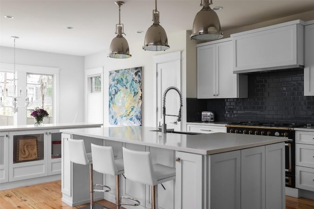 606 E 42nd St, Austin, TX 78751 - kitchen with stainless steel stove, a sink, tasteful backsplash, light countertops, and light wood-style floors