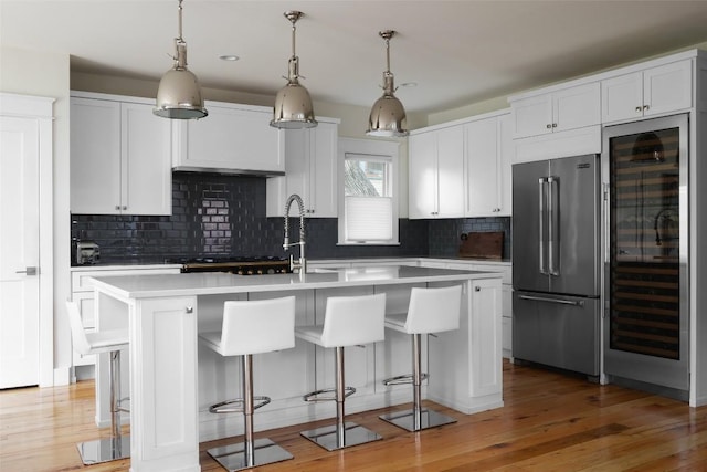 606 E 42nd St, Austin, TX 78751 - kitchen with high end fridge, beverage cooler, an island with sink, light countertops, and decorative backsplash