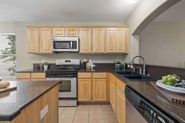 6220 Seville Dr, Austin, TX 78724 - kitchen with appliances with stainless steel finishes, light brown cabinets, arched walkways, and light tile patterned flooring