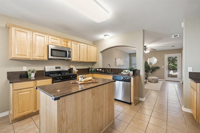 6220 Seville Dr, Austin, TX 78724 - kitchen featuring appliances with stainless steel finishes, light brown cabinetry, light tile patterned floors, arched walkways, and a ceiling fan
