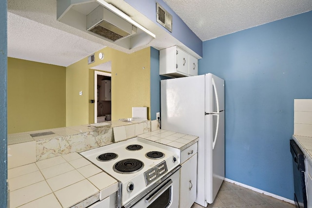 500 E Riverside Dr Unit 146, Austin, TX 78704 - kitchen featuring white appliances, tile counters, a textured ceiling, white cabinets, and light tile patterned floors