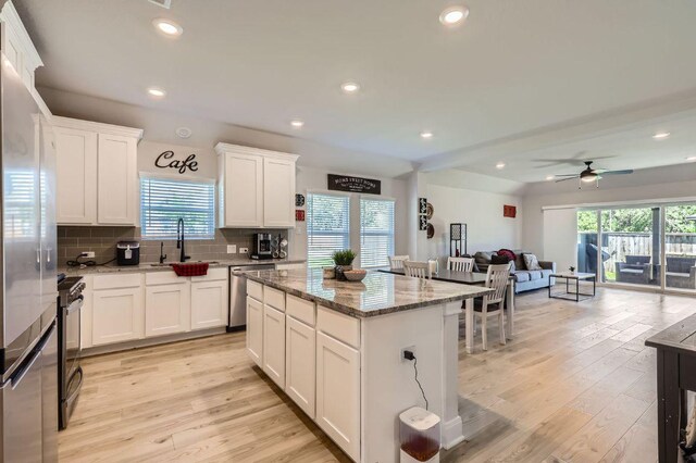 116 Angel Oak Way, San Marcos, TX 78666 - kitchen featuring stone countertops, tasteful backsplash, light wood-type flooring, open floor plan, and appliances with stainless steel finishes