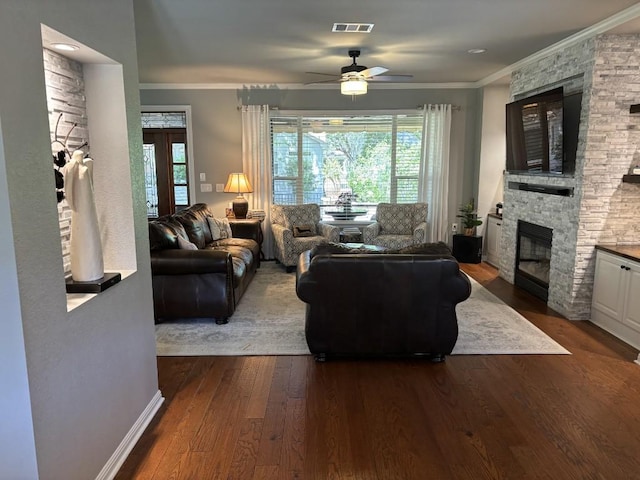 122 Camp Dr, Georgetown, TX 78633 - living area featuring a stone fireplace, healthy amount of natural light, ceiling fan, dark wood finished floors, and crown molding