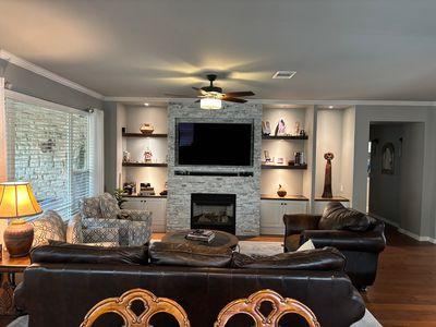 122 Camp Dr, Georgetown, TX 78633 - living room featuring ornamental molding, ceiling fan, wood finished floors, a stone fireplace, and built in shelves