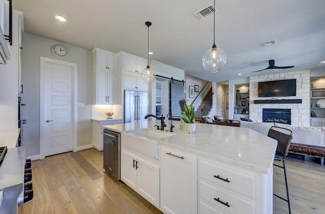 304 Ashburn Cv, Austin, TX 78738 - kitchen featuring appliances with stainless steel finishes, a sink, ceiling fan, light wood-type flooring, and recessed lighting
