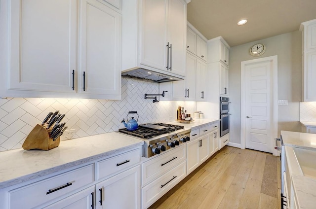 304 Ashburn Cv, Austin, TX 78738 - kitchen with stainless steel appliances, white cabinetry, light wood-style flooring, backsplash, and light stone countertops