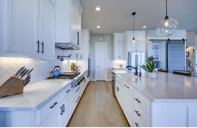 304 Ashburn Cv, Austin, TX 78738 - kitchen with stainless steel appliances, a sink, light wood-type flooring, white cabinets, and recessed lighting