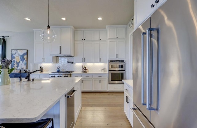304 Ashburn Cv, Austin, TX 78738 - kitchen featuring appliances with stainless steel finishes, light wood-style floors, white cabinetry, tasteful backsplash, and recessed lighting