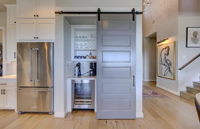 304 Ashburn Cv, Austin, TX 78738 - kitchen featuring high quality fridge, beverage cooler, light wood-type flooring, white cabinetry, and baseboards