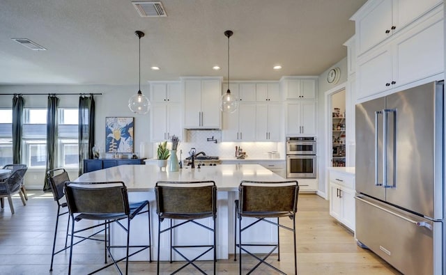 304 Ashburn Cv, Austin, TX 78738 - kitchen with appliances with stainless steel finishes, light countertops, light wood-type flooring, white cabinets, and recessed lighting