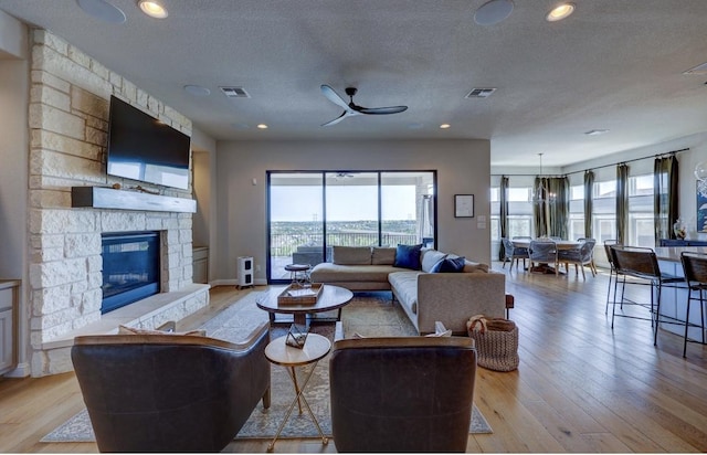304 Ashburn Cv, Austin, TX 78738 - living area featuring a fireplace, light wood-style floors, a textured ceiling, and a ceiling fan