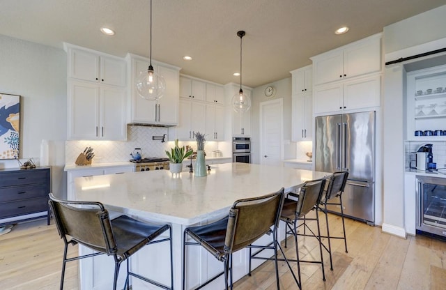 304 Ashburn Cv, Austin, TX 78738 - kitchen featuring appliances with stainless steel finishes, beverage cooler, light wood-type flooring, white cabinets, and recessed lighting