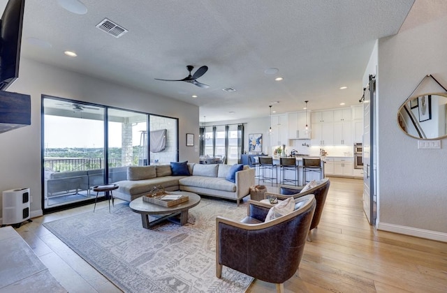 304 Ashburn Cv, Austin, TX 78738 - living room featuring ceiling fan, light wood finished floors, baseboards, recessed lighting, and a textured ceiling