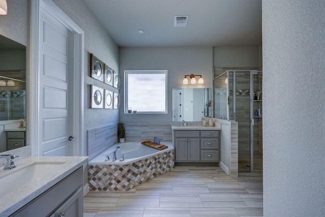 304 Ashburn Cv, Austin, TX 78738 - full bathroom with a stall shower, a garden tub, two vanities, and a textured wall