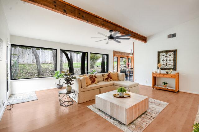 6304 Whitemarsh Valley Walk, Austin, TX 78746 - living area with a ceiling fan, visible vents, baseboards, vaulted ceiling with beams, and light wood-style flooring