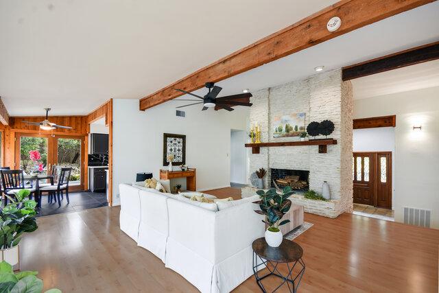 6304 Whitemarsh Valley Walk, Austin, TX 78746 - living room with a ceiling fan, visible vents, a stone fireplace, and wood finished floors