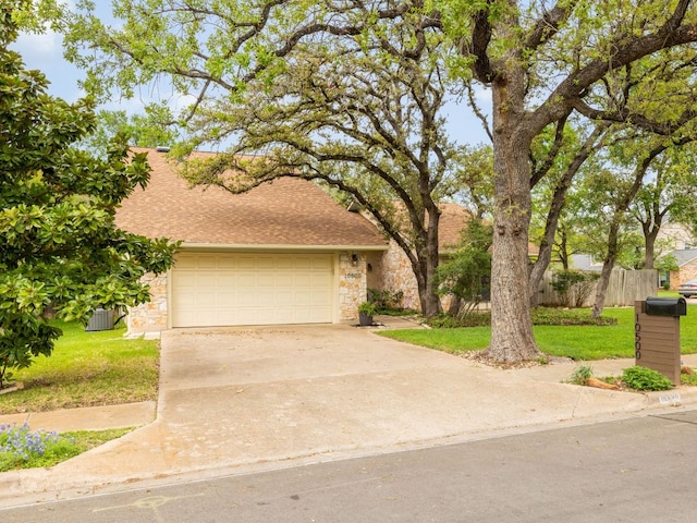 view of front facade featuring a front lawn, fence, stone siding, and concrete driveway
