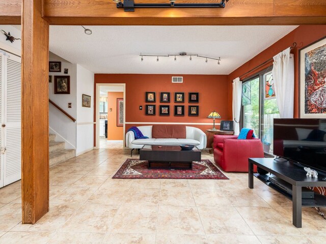 tiled living room featuring visible vents and stairway