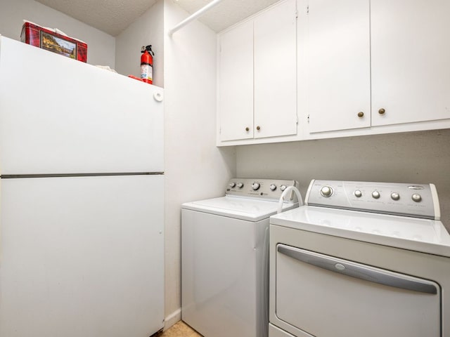 laundry area with a textured ceiling, washing machine and clothes dryer, and cabinet space