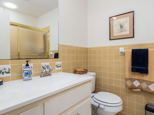 full bath featuring tile walls, toilet, a textured ceiling, vanity, and a stall shower