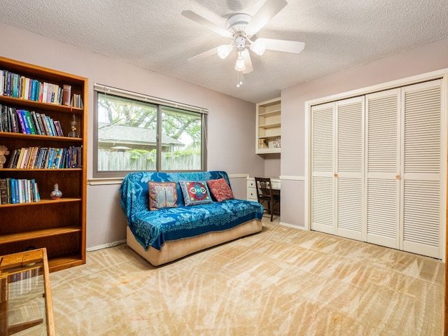 living area featuring baseboards, carpet, a textured ceiling, and a ceiling fan
