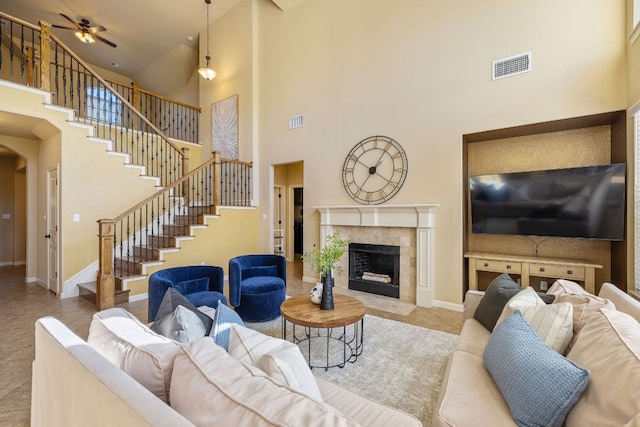 1812 Buffalo Thunder, Leander, TX 78641 - living area featuring a towering ceiling, stairs, baseboards, ceiling fan, and a tile fireplace