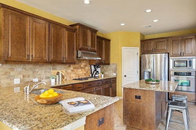 1812 Buffalo Thunder, Leander, TX 78641 - kitchen with stainless steel appliances, range hood, a breakfast bar, a sink, and light stone countertops
