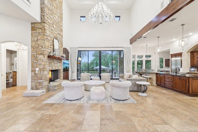 living room with a chandelier, stone tile flooring, a high ceiling, and a fireplace