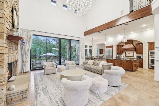 living area with arched walkways, an inviting chandelier, a toaster, a fireplace, and a high ceiling