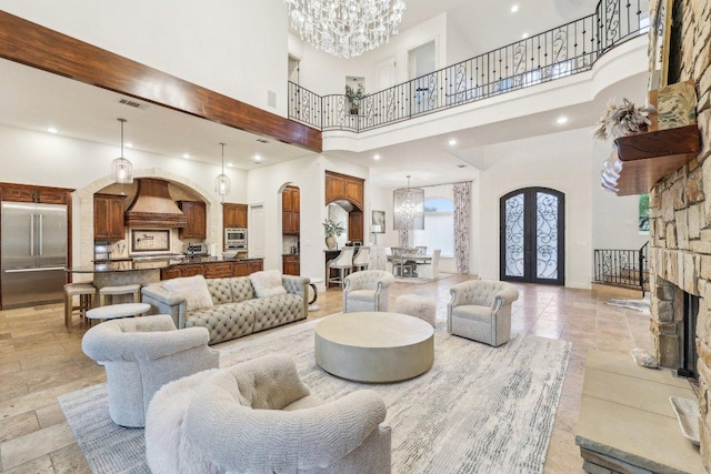living room with arched walkways, an inviting chandelier, visible vents, french doors, and a towering ceiling